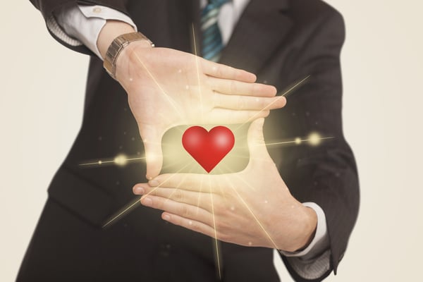 Hands creating a form with shining red heart in the center